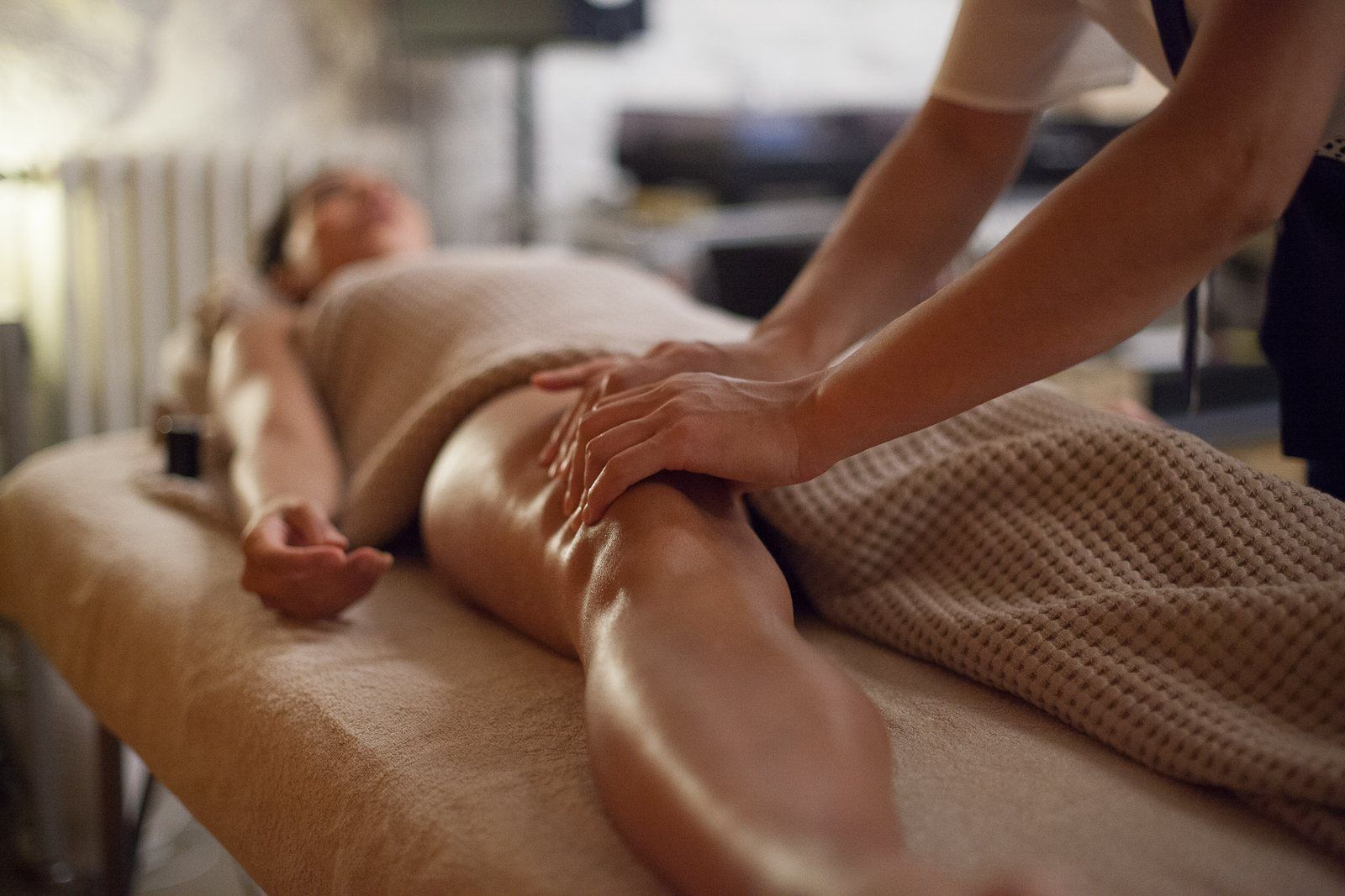 Drainage lymphatique des jambes, cliente allongée sous un linge gaufré